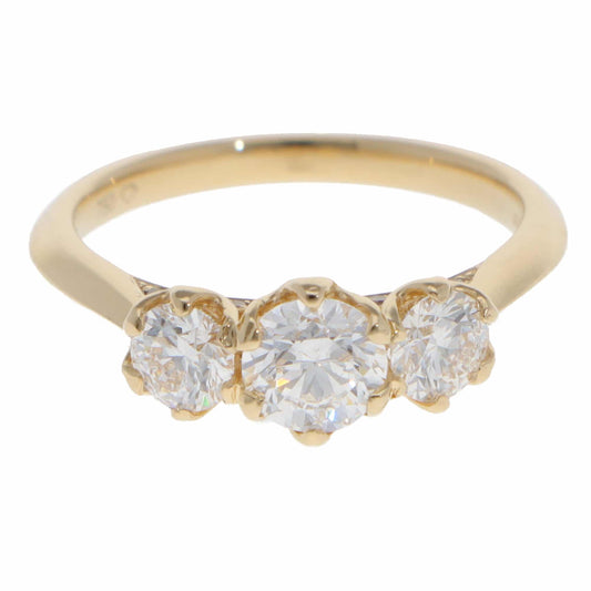 A three stone diamond ring in yellow gold, on a white background