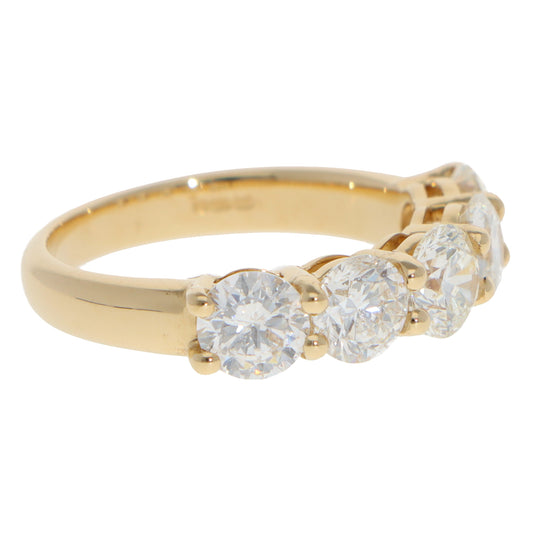A five stone round brilliant cut diamond ring in yellow gold, on a white background