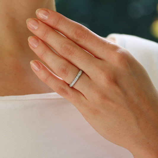 A white metal diamond set full eternity band ring, modelled on the hand of a woman