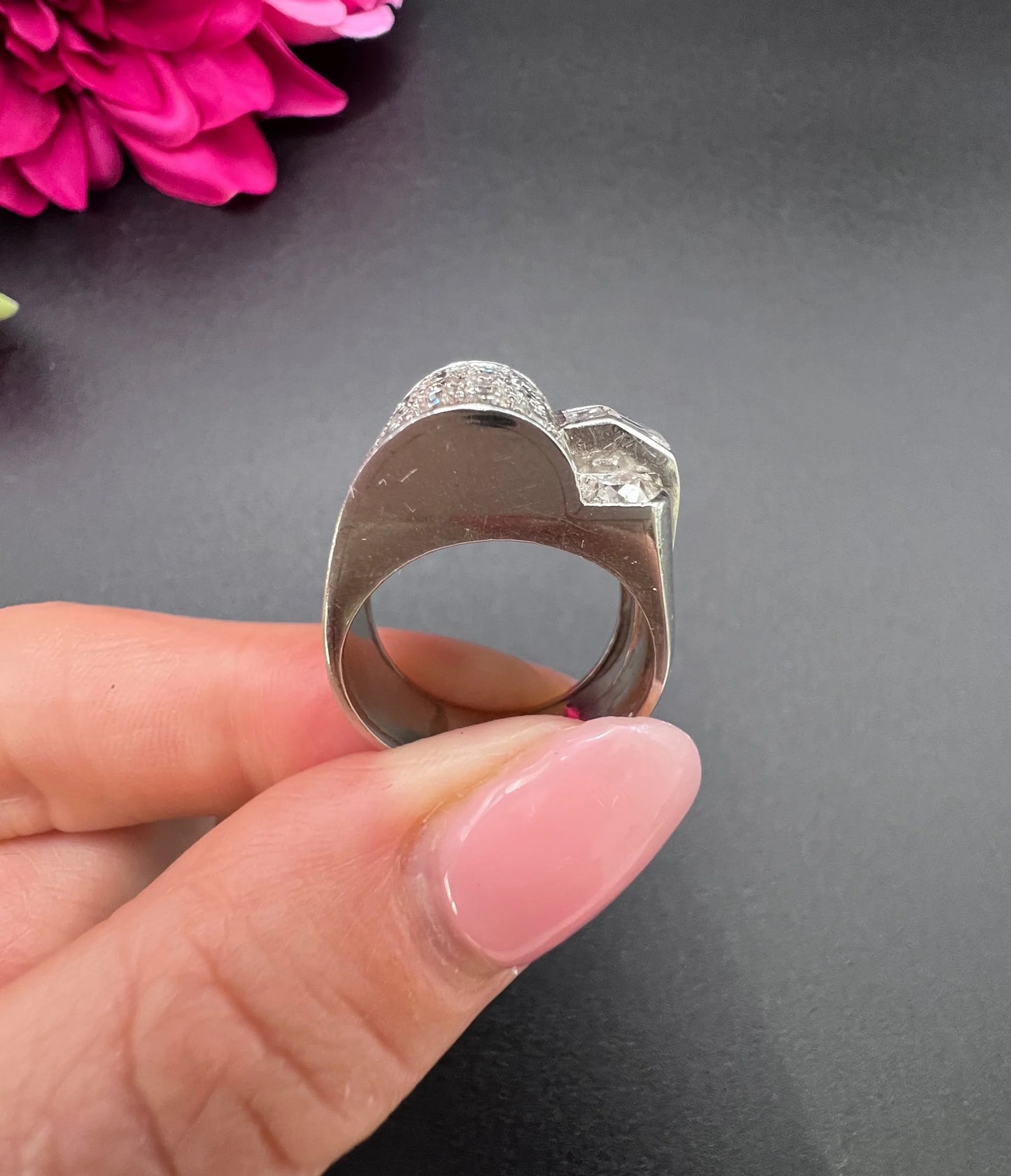 A round diamond tank style cocktail ring in platinum, held in a hand