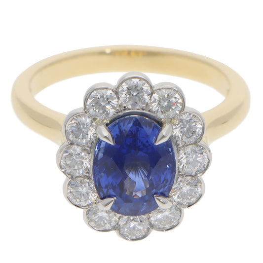 An oval sapphire and round diamond cluster ring in yellow gold and platinum, on a white background