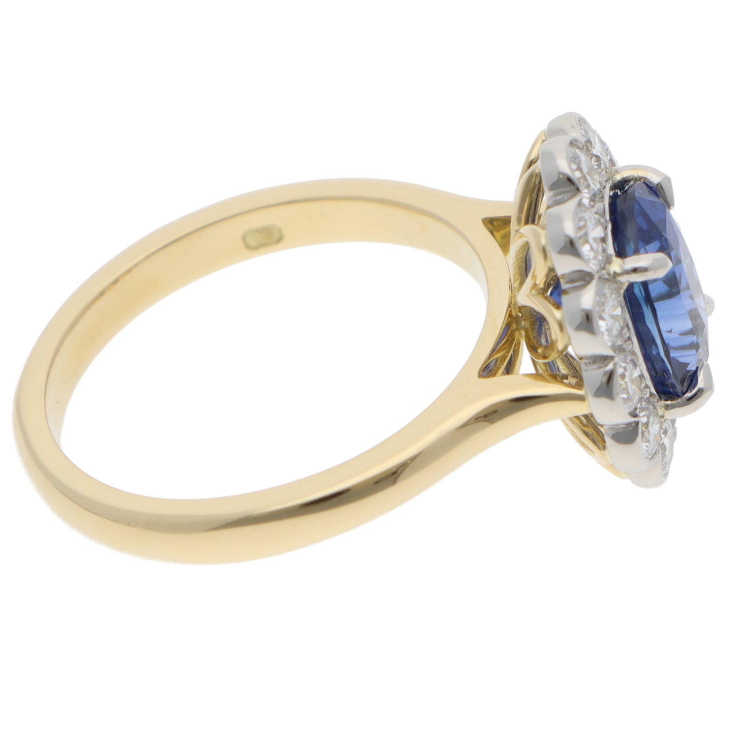 An oval sapphire and round diamond cluster ring in yellow gold and platinum, on a white background