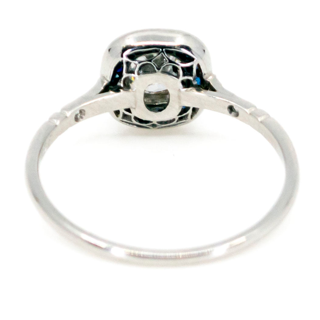 A cushion cut diamond halo cluster ring with sapphires in platinum