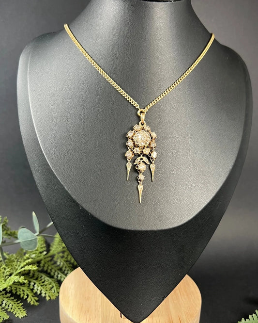 A yellow gold pendant with old cut diamonds, with a gold chain, modelled on a black jewellery bust