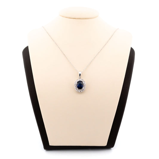 An oval sapphire and diamond cluster pendant in white gold, on a white gold chain