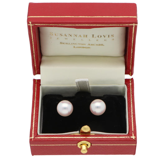 A pair of pearl stud earrings with yellow gold fittings, in an earring box, on a white background