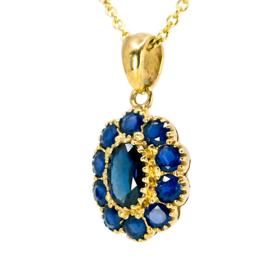 An oval cluster pendant with blue sapphires in yellow gold, on a gold chain
