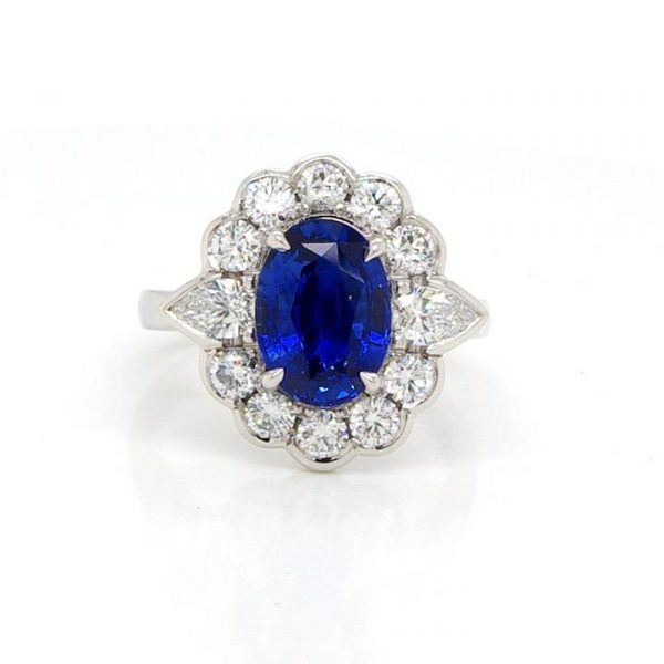 Edwardian Style Sapphire, Diamond and Platinum Oval Cluster Ring; central 2.98ct oval faceted sapphire within a surround of 1.10cts collet-set brilliant cut diamonds, with a trilliant cut diamond to each shoulder