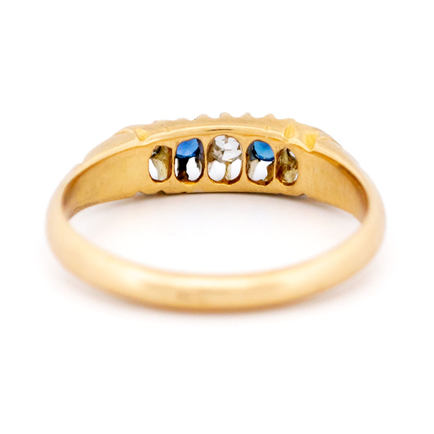 A sapphire and diamond five stone ring in yellow gold, on a white background