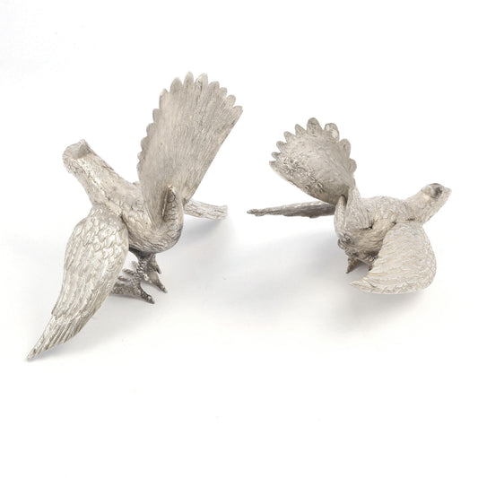 Two silver bird sculptures on a white background