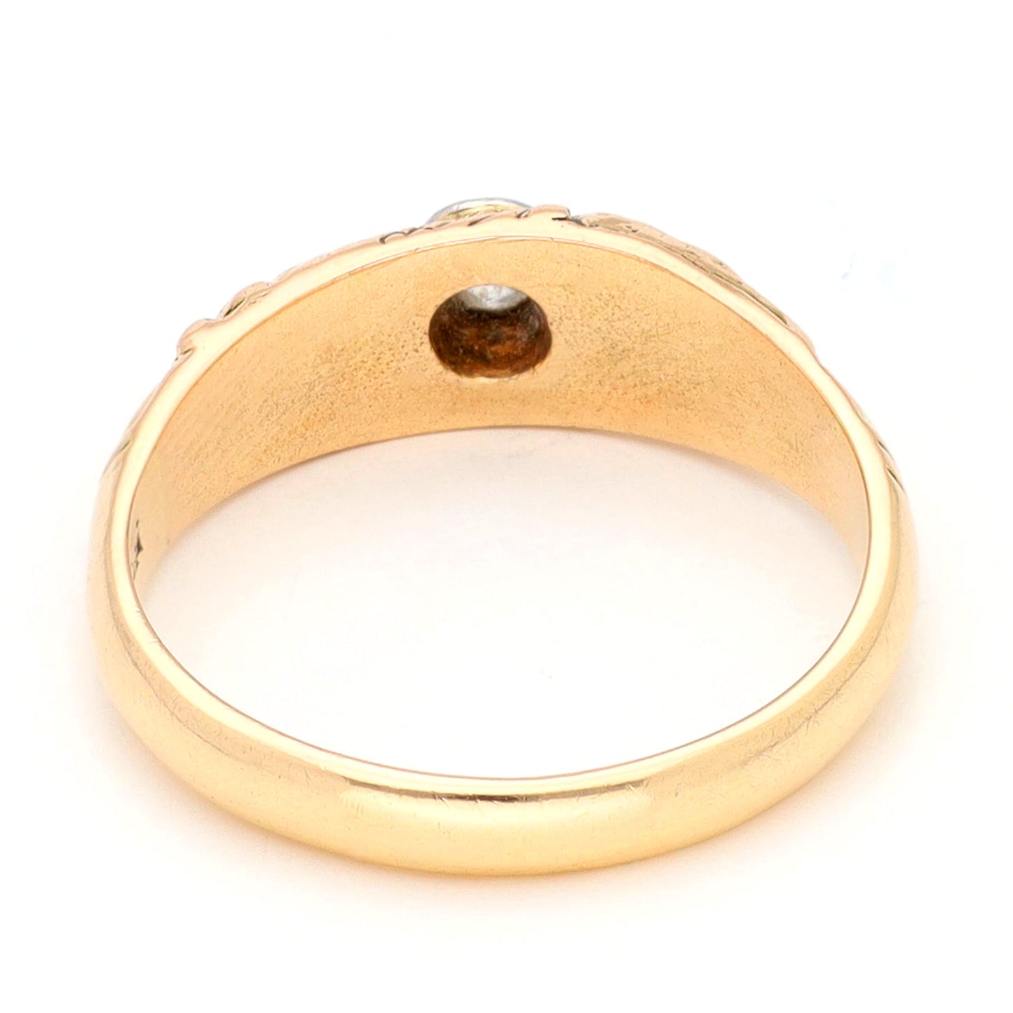A yellow gold ring with a single old cut diamond bezel set in white gold, with scroll engraving, against a white background