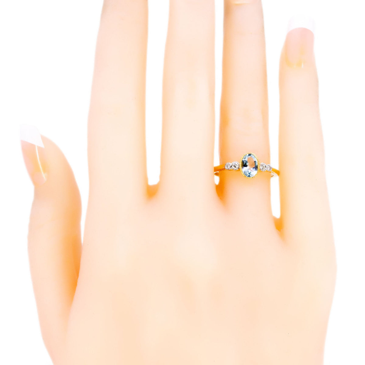 An oval aquamarine and round diamond ring in yellow and white gold, modelled on a hand