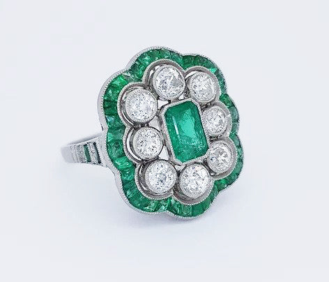 Vintage Emerald and Diamond Floral Cluster Dress Ring; emerald-cut emerald surrounded by eight round-cut diamonds and calibre-cut emeralds, in platinum