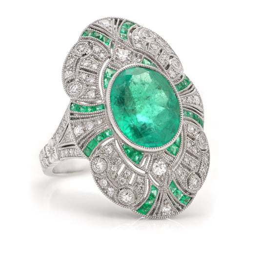 Oval cut emerald ring surround by emeralds and diamonds set in platinum.
