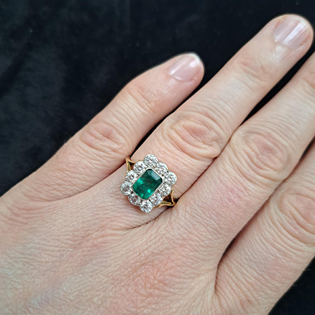 An emerald and diamond rubover set cluster ring in yellow and white gold, modelled on a hand