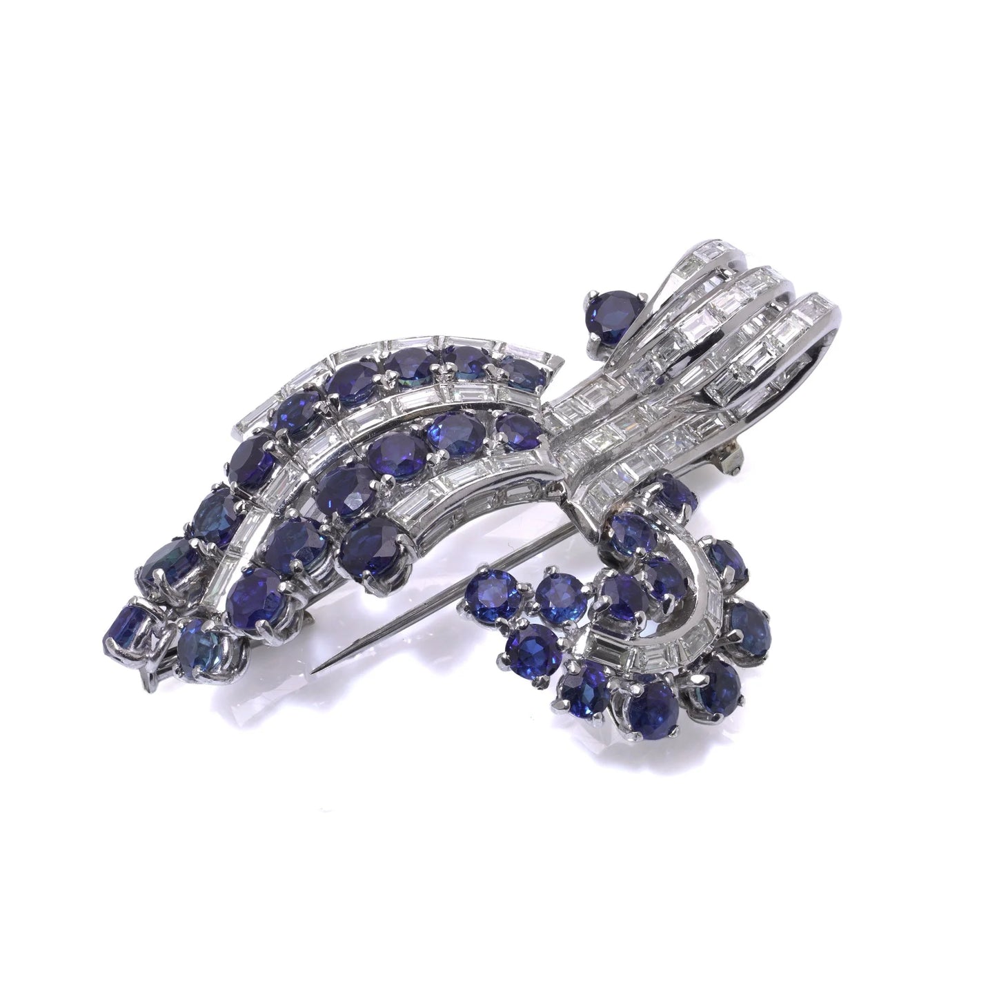 A decorative baguette cut diamond and round sapphire brooch in white metal, on a white background
