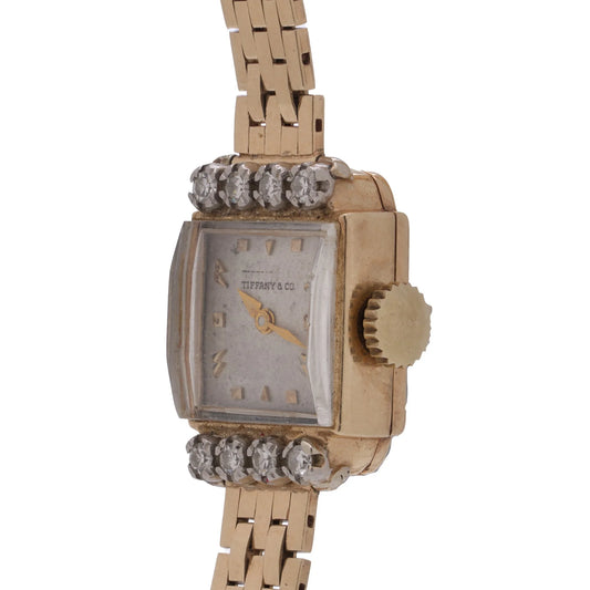 A yellow gold Tiffany & Co. diamond set wristwatch with a brick link bracelet, on a white background