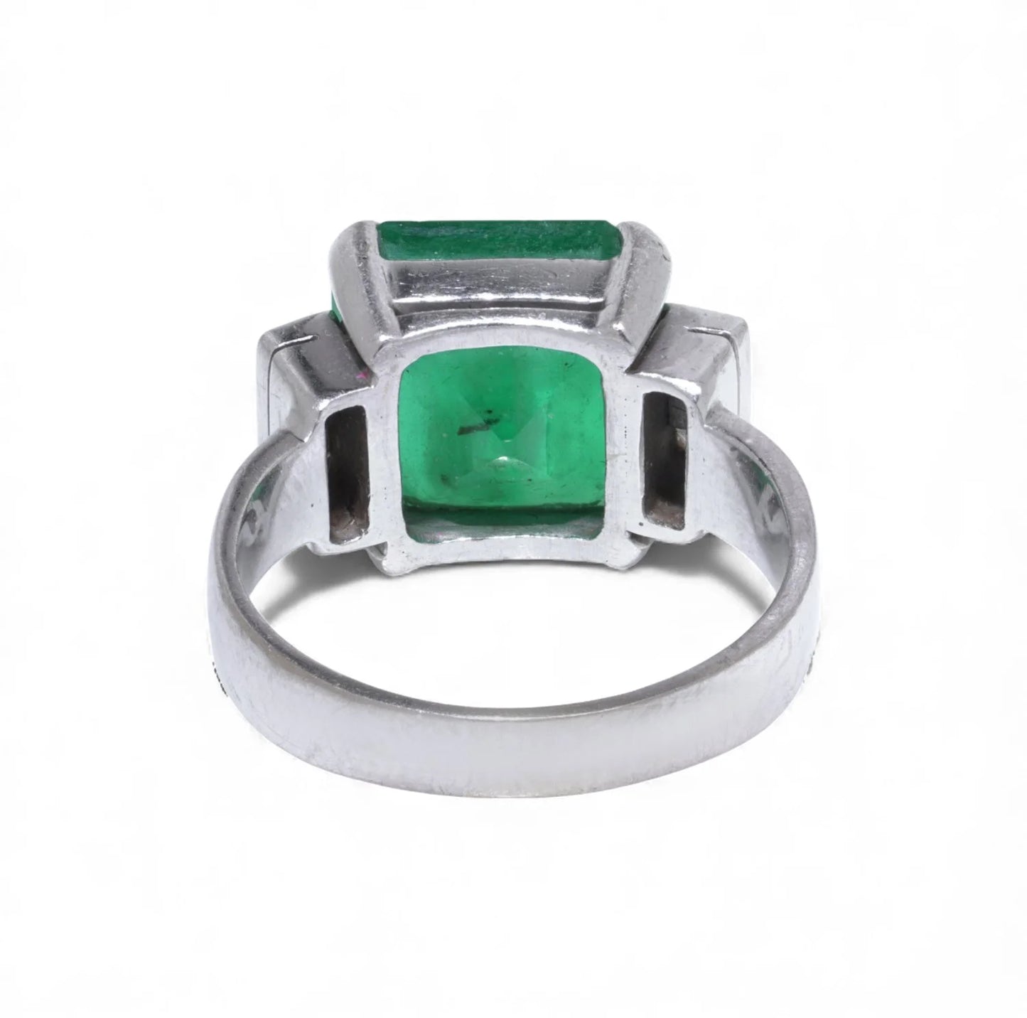 An emerald and square diamond five stone ring in white gold, on a white background