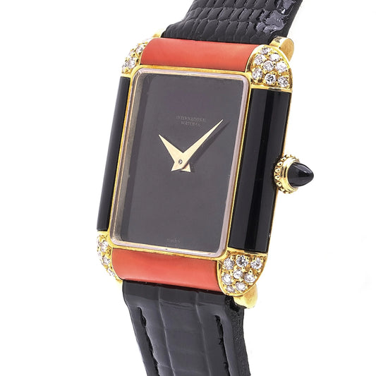 A black dial vintage dress watch with coral, onyx and diamonds in yellow gold on a black leather strap, on a white background