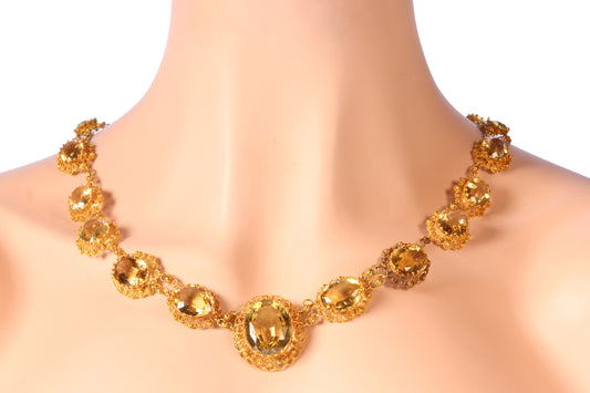 An intricate yellow gold necklace set with oval citrines in filigree mounts, modelled on a neck