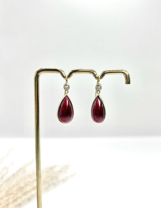 A pair of teardrop shaped cabochon garnet and round diamond drop earrings in gold