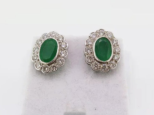 Emerald and Diamond Oval Cluster Stud Earrings; 1.66cts oval faceted emeralds surrounded by 0.80cts sparkling diamonds, in 18ct white gold