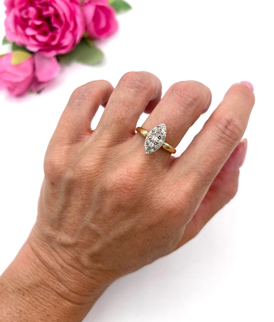 A navette cluster ring set with old cut diamonds in yellow gold, modelled on a hand
