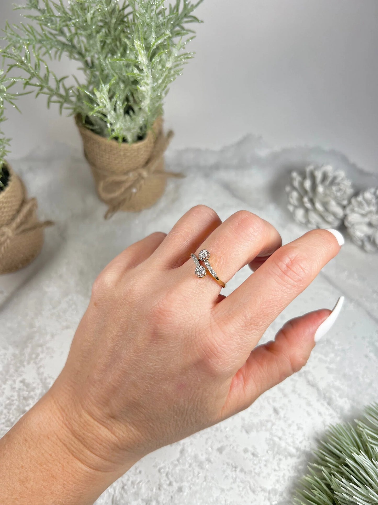 A two stone diamond crossover ring in yellow and white gold, modelled on a hand