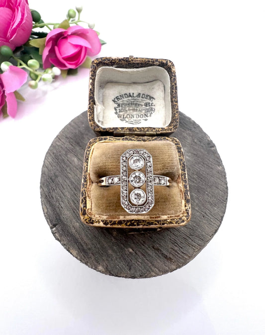 A diamond open cluster ring with three principal diamonds, in yellow and white gold, in a ring box