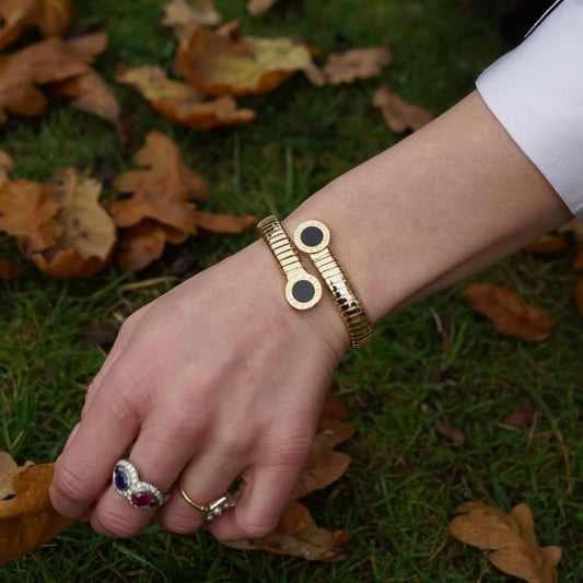 Vintage Bvlgari 18ct Yellow Gold and Onyx Tubogas Bangle Bracelet, 18ct yellow gold tubogas flexible sprung cuff made of coiled gas pipe links with terminals of circular onyx plaques encased in a polished surround engraved with the BVLGARI BVLGARI motif. Made in Italy, Alexandria, Circa 1990s