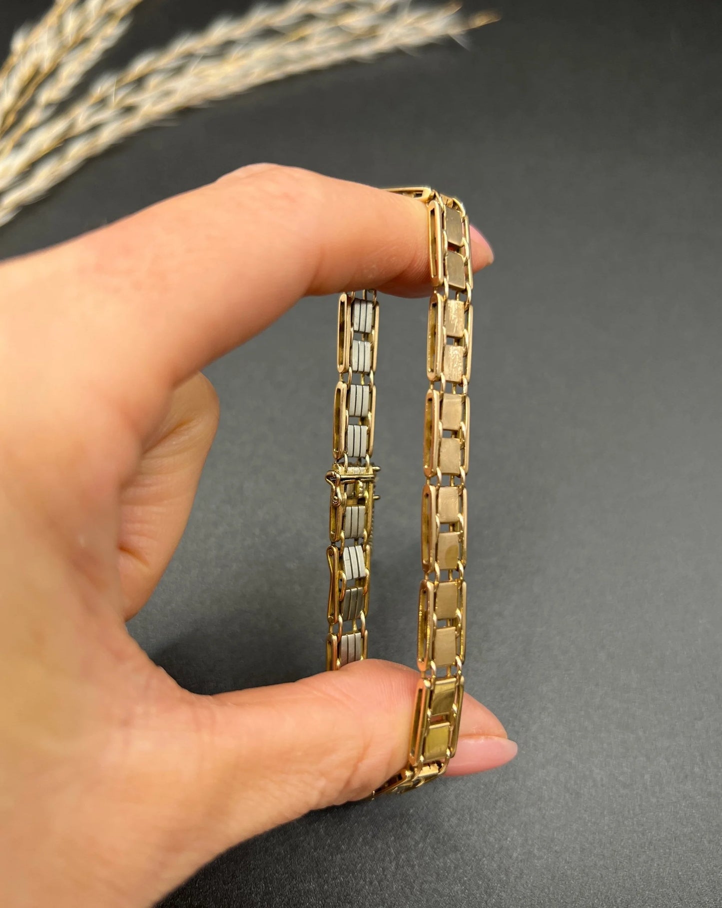 A gold and platinum gate bracelet, held in a hand