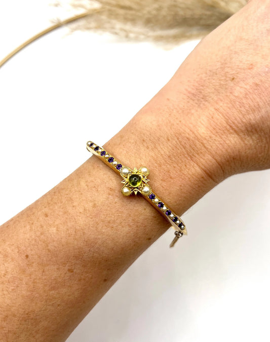 A peridot, amethyst and pearl bangle in yellow gold, modelled on a wrist