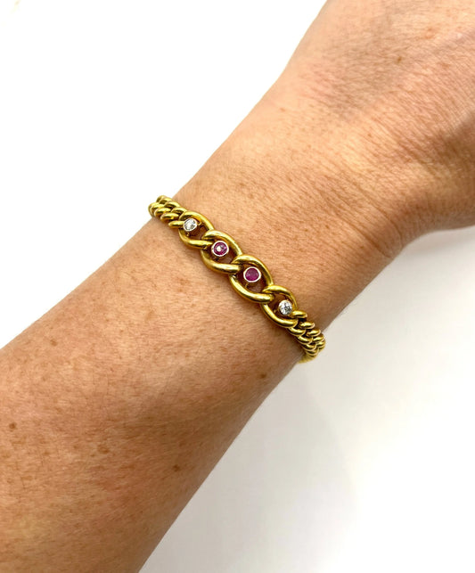 A yellow gold curb link bracelet with rubies and diamonds, modelled on a wrist