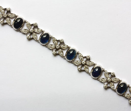 Vintage 15ct Sapphire and Diamond Bracelet; A white gold bracelet with eleven cabochon-cut sapphires alternated with 2.50cts diamond set flowers, Circa 1950