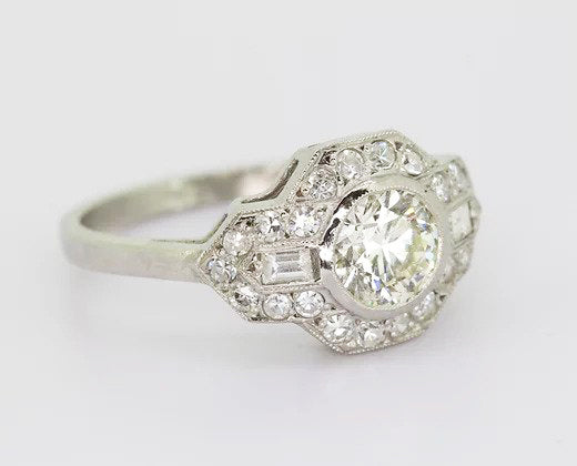 Art Deco Style Diamond Cluster Ring; 0.80ct brilliant-cut diamond with geometric diamond surround, baguette cut diamonds on the shoulders, 18ct white gold.