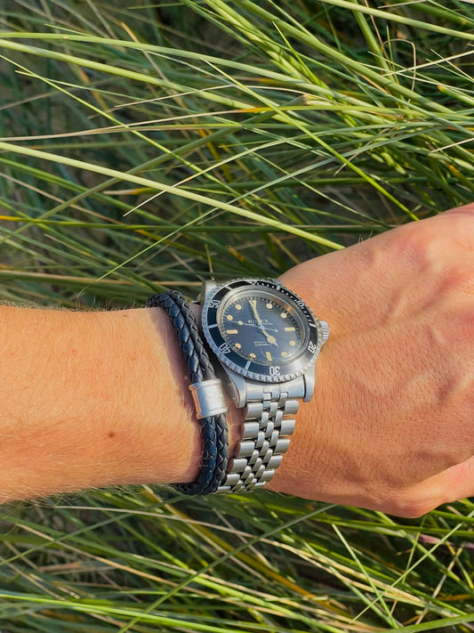 A Rolex Submariner wristwatch in stainless steel with a black dial and jubilee bracelet, modelled on a man's wrist