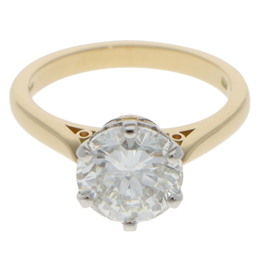 A single stone round brilliant cut diamond ring in yellow gold and platinum, on a white background