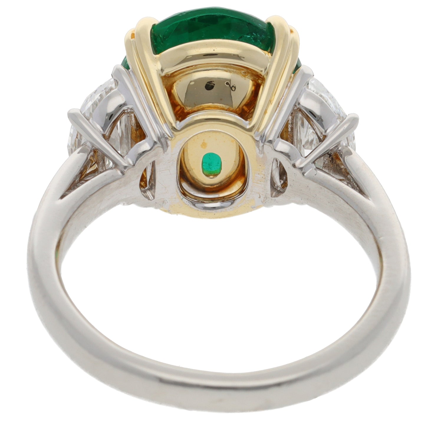 A three stone emerald and diamond ring in platinum and yellow gold, on a white background