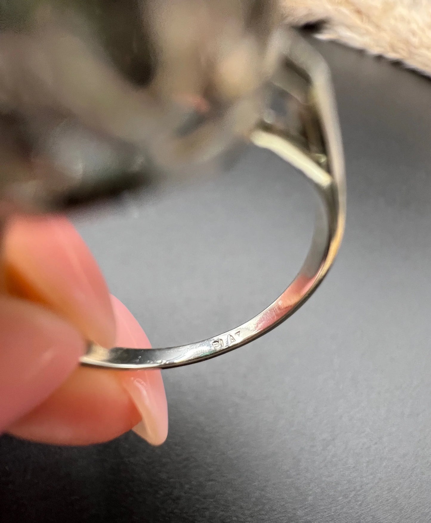 A close-up of a PLAT stamped ring shank, held in a hand