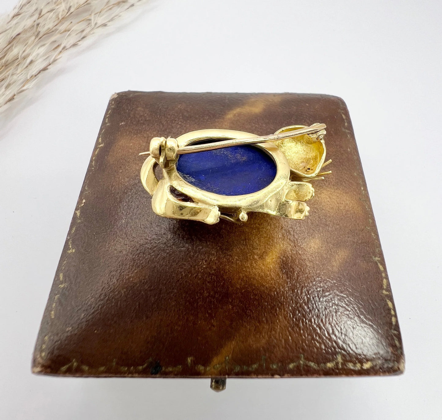 A yellow gold cat brooch with a lapis lazuli body