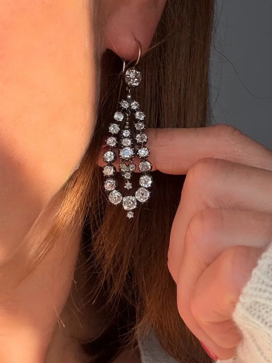 A pair of old cut diamond drop earrings in silver and gold, modelled in an ear