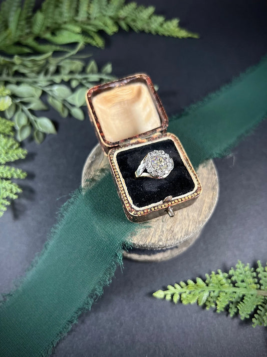 A diamond cluster ring in two tone gold, in an antique ring box
