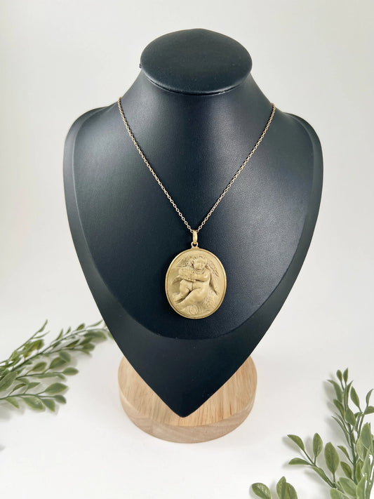 An oval cherub lava cameo pendant in yellow gold, on a chain, on a black bust