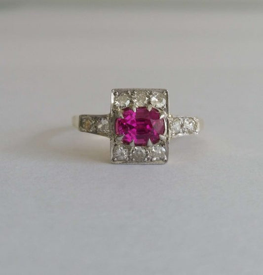 Art Deco Pink Sapphire and Old Cut Diamond Cluster Ring; an oval pink sapphire of intense colour is set in 18ct gold and platinum surrounded by small old cut diamonds. Circa 1920s