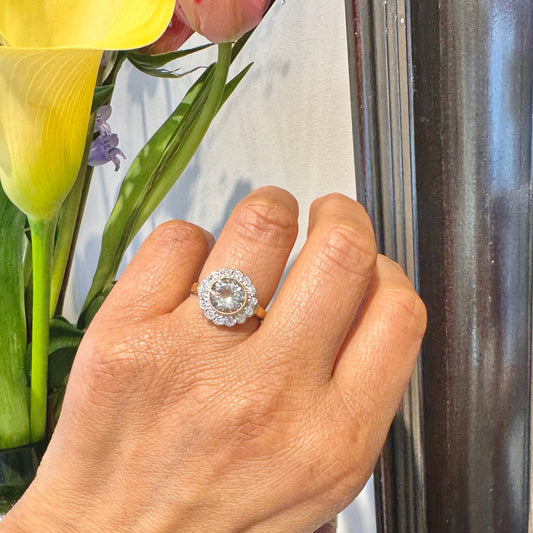 A flower shaped aquamarine and diamond cluster ring in yellow and white gold, modelled on a hand
