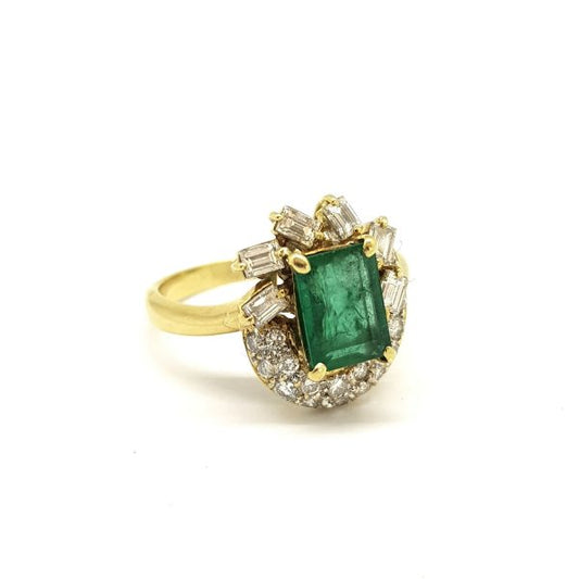 Vintage Emerald and Diamond Cluster Dress Ring; 2ct emerald-cut emerald surrounded by 1.20cts baguette and brilliant cut diamonds, in 18ct yellow gold
