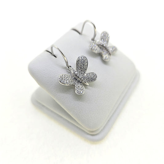 A pair of butterfly shaped diamond set earrings with hook fittings in white gold, on a white background