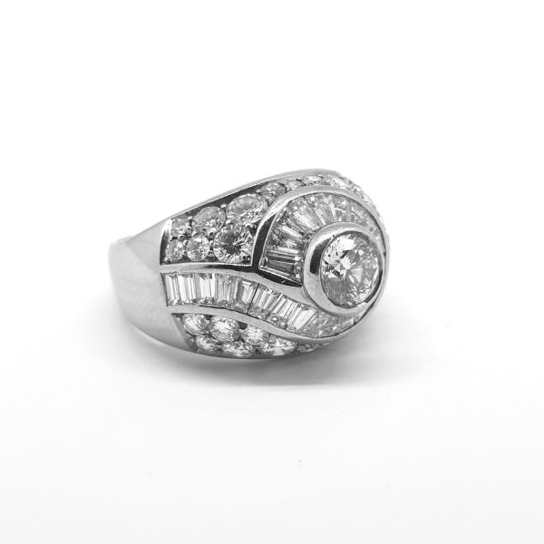 Geometric Diamond Bombe Dress Ring; central brilliant-cut diamond encircled by a tapered baguette-cut diamond swirl surrounded by diamonds, 2.75 carat total, in 18ct white gold