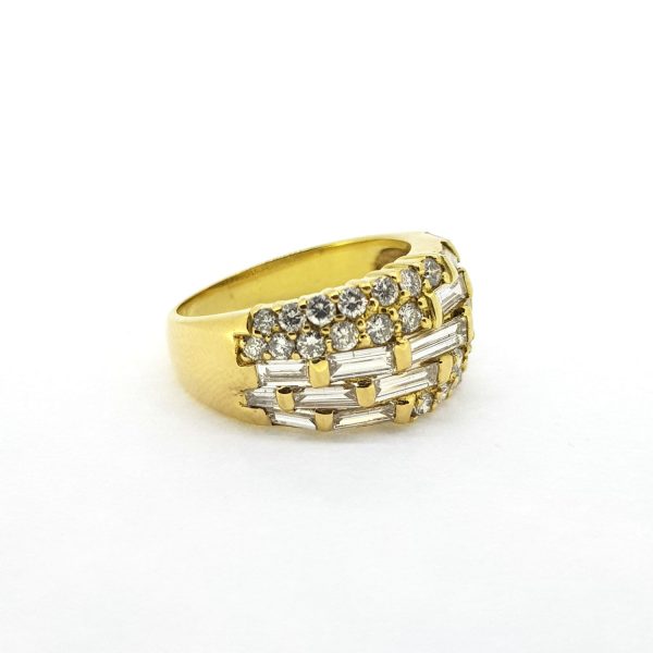Modern Baguette and Brilliant Cut Diamond Dress Ring; 18ct yellow gold band set with brilliant and baguette-cut diamonds in eye-catching off-set asymmetrical pattern