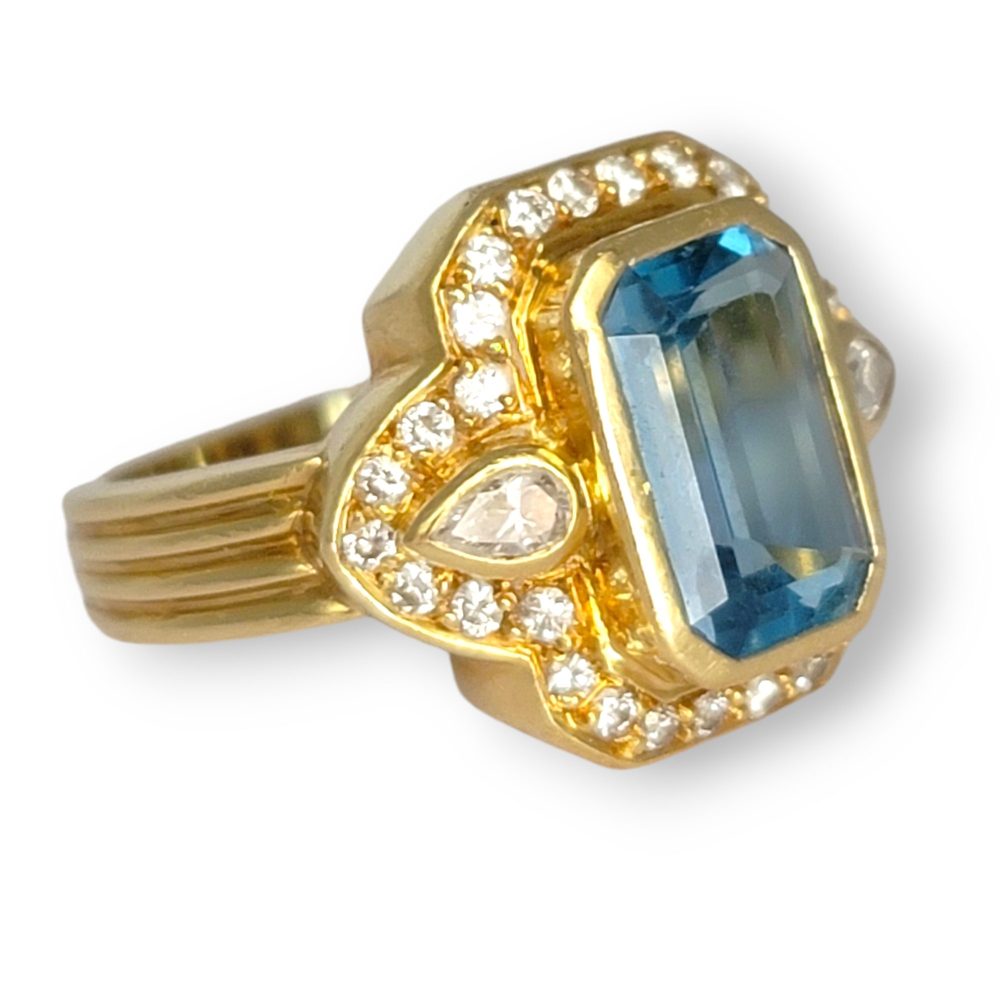 4.4ct Santa Maria Aquamarine and Diamond Cluster Dress Ring, 4.40ct emerald-cut Santa Maria aquamarine flanked by pear-cut diamonds all within diamond border in 18ct yellow gold